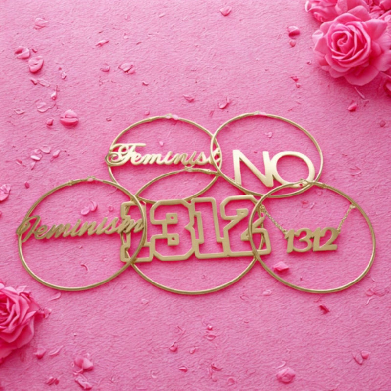 Feministische Ohrringe: goldene Creolen mit Schriftzügen Feminism, Feminist, NO und 1312 aus Edelstahl auf rosa Hintergrund
