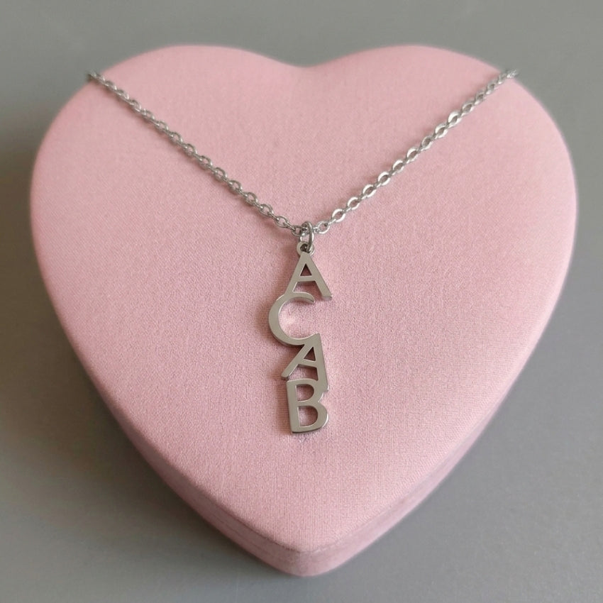 ACAB 1312 Halskette in Silber – Edelstahlkette mit senkrechtem ACAB-Buchstabenanhänger auf rosa Herz-Deko, Bling Bling Feministas