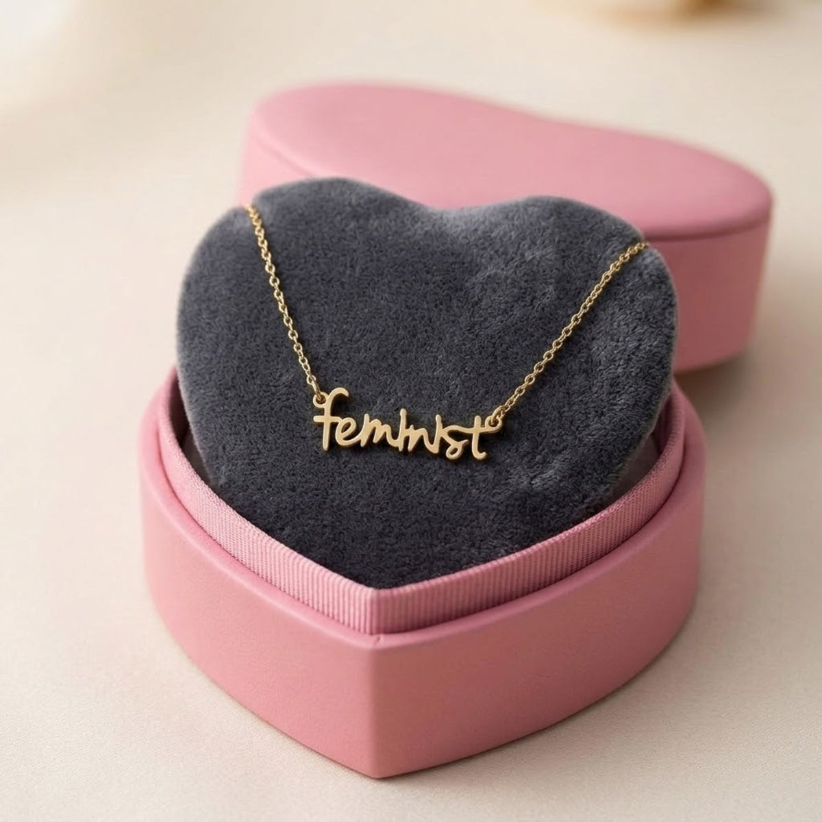 feminist Halskette in Gold aus Edelstahl mit Schriftzug feminist in Schreibschrift in rosa Herz-Schmuckschachtel