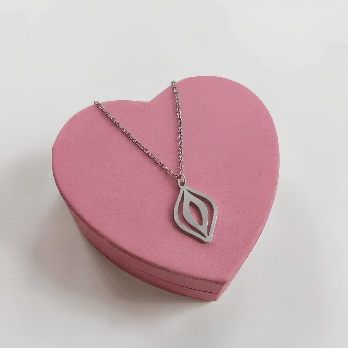Feministische Vulva Kette in Silber aus Edelstahl mit stilisiertem Vulva-Anhänger auf rosa Herzschachtel
