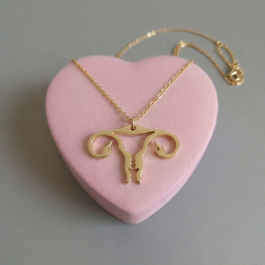 Uterus-Halskette in Gold – Edelstahlkette mit Gebärmutter-Anhänger mit Mittelfinger auf rosa Herz-Deko, Bling Bling Feministas
