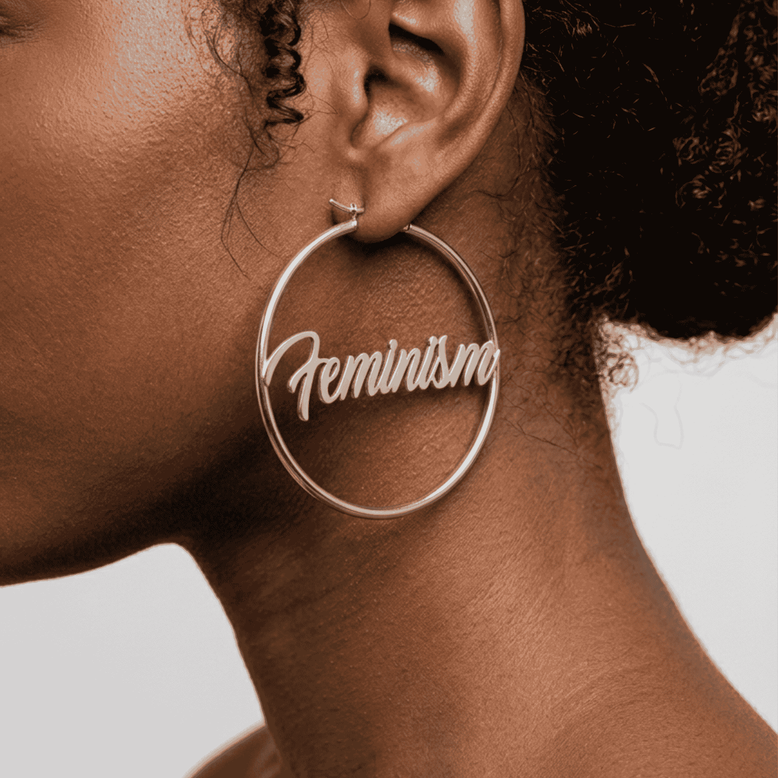 Silberne Feminism Creole 60mm am Ohr getragen – großer Edelstahl-Ohrring mit Schriftzug von Bling Bling Feministas