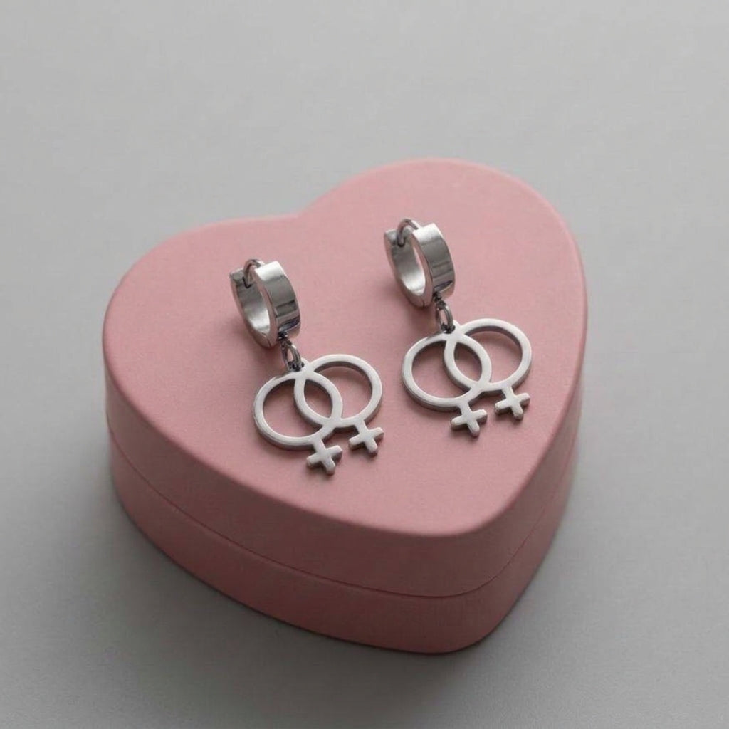 Doppel Venus Symbol Ohrringe in Silber – feministische Edelstahl-Creolen mit zwei verschlungenen Frauensymbolen ♀♀ auf rosa Herzschachtel, Bling Bling Feministas