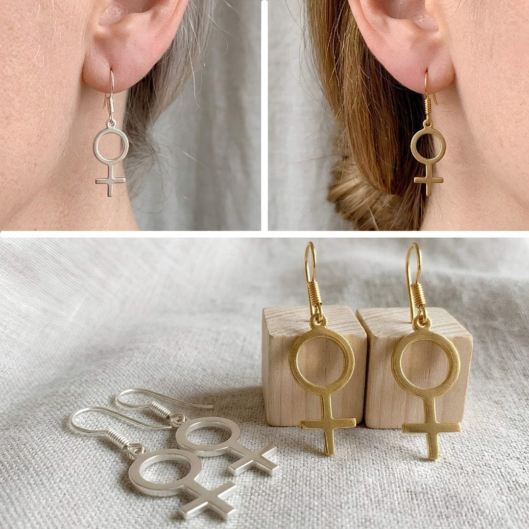 Venus Symbol Ohrringe in Silber und Gold – getragen am Ohr und als Produktfoto mit Holzwürfel, feministischer Edelstahl-Schmuck von Bling Bling Feministas